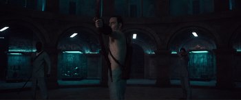Movie still from “Assassin's Creed” (2016), directed by Justin Kurzel – A man holding a bow and arrow in a dark room; Medium shot, Low angle