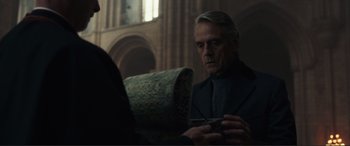 Movie still from “Assassin's Creed” (2016), directed by Justin Kurzel – An older man is looking at a piece of paper; Medium shot, Over the shoulder angle