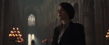 Movie still from “Assassin's Creed” (2016), directed by Justin Kurzel – A woman standing in a dark room looking off into the distance; Medium shot, Low angle