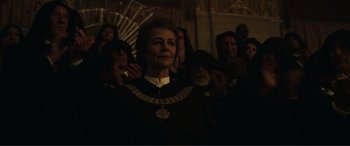 Movie still from “Assassin's Creed” (2016), directed by Justin Kurzel – An older woman wearing a black and gold outfit; Medium shot, Low angle