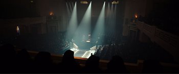 Movie still from “Assassin's Creed” (2016), directed by Justin Kurzel – A crowd of people sitting in front of stage lights; Extreme Wide shot, High angle