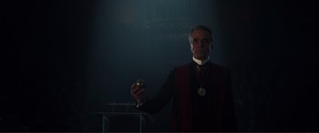 Movie still from “Assassin's Creed” (2016), directed by Justin Kurzel – A man in a red and black jacket holding a medal; Medium shot, Low angle