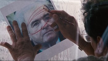 Movie still from “Assassins” (1995), directed by Richard Donner – A person holding up a picture of a man; Extreme Close Up shot, Over the shoulder angle