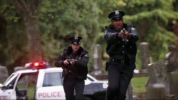 Movie still from “Assassins” (1995), directed by Richard Donner – A couple of police officers standing next to each other on a street; Wide shot, Low angle