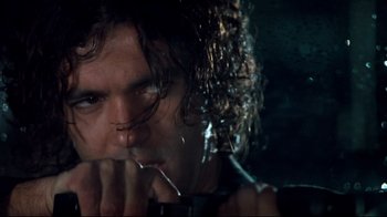 Movie still from “Assassins” (1995), directed by Richard Donner – A person holding a toothbrush in his mouth; Close Up shot, Low angle