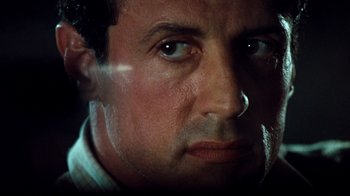 Movie still from “Assassins” (1995), directed by Richard Donner – Sylvester stallone's face in a dark room; Close Up shot, Low angle