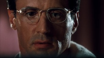 Movie still from “Assassins” (1995), directed by Richard Donner – A person wearing glasses; Extreme Close Up shot, Low angle