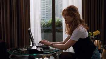 Movie still from “Assassins” (1995), directed by Richard Donner – A woman sitting in front of a laptop computer; Medium shot, Low angle