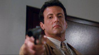 Movie still from “Assassins” (1995), directed by Richard Donner – A person holding a gun; Close Up shot, Low angle