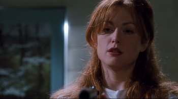 Movie still from “Assassins” (1995), directed by Richard Donner – A woman holding a gun while looking at the camera; Close Up shot, Low angle