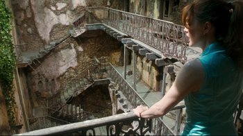 Movie still from “Assassins” (1995), directed by Richard Donner – A woman standing on the stairs of an abandoned building; Wide shot, High angle