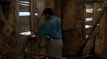 Movie still from “Assassins” (1995), directed by Richard Donner – A man standing in front of an old window; Medium shot, Low angle