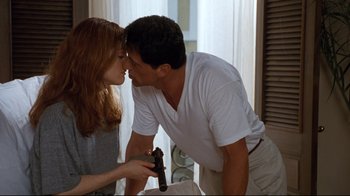 Movie still from “Assassins” (1995), directed by Richard Donner – A man and a woman are holding a gun in their hands; Medium shot, Low angle