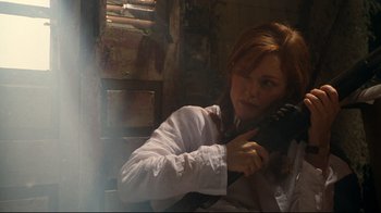 Movie still from “Assassins” (1995), directed by Richard Donner – A red haired woman holding a gun in her hand; Medium shot, Low angle