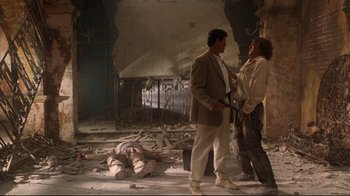 Movie still from “Assassins” (1995), directed by Richard Donner – Two men standing in an abandoned building next to a dead body; Wide shot, Low angle