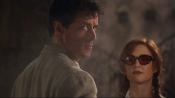Movie still from “Assassins” (1995), directed by Richard Donner – A man and a woman standing next to each other; Close Up shot, Low angle