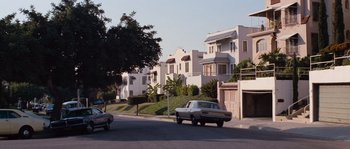 Movie still from “Assault on Precinct 13” (1976), directed by John Carpenter – A car driving down a street next to a building; Extreme Wide shot, Low angle