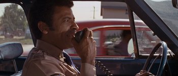 Movie still from “Assault on Precinct 13” (1976), directed by John Carpenter – A man talking on a phone while sitting in the back of a car; Close Up shot, Low angle