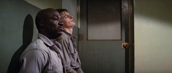 Movie still from “Assault on Precinct 13” (1976), directed by John Carpenter – Two men are sitting in front of each other; Medium shot, Over the shoulder angle