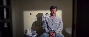 Movie still from “Assault on Precinct 13” (1976), directed by John Carpenter – A man sitting on a chair in front of a urinal; Medium shot, High angle