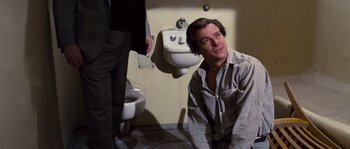 Movie still from “Assault on Precinct 13” (1976), directed by John Carpenter – A man in a room next to a urinal; Medium shot, Over the shoulder angle