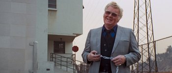 Movie still from “Assault on Precinct 13” (1976), directed by John Carpenter – A man in a suit and tie holding a chain; Medium shot, Low angle