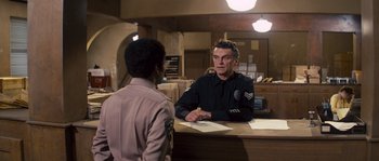 Movie still from “Assault on Precinct 13” (1976), directed by John Carpenter – A man in a police uniform talking to a man in a uniform; Medium shot, Over the shoulder angle