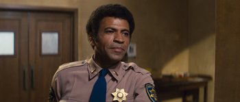 Movie still from “Assault on Precinct 13” (1976), directed by John Carpenter – A man in a police uniform is looking at the camera; Close Up shot, Low angle