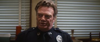 Movie still from “Assault on Precinct 13” (1976), directed by John Carpenter – A person wearing a police uniform; Close Up shot, Over the shoulder angle