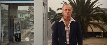 Movie still from “Assault on Precinct 13” (1976), directed by John Carpenter – A man wearing a jacket and a plaid shirt; Medium shot, Low angle