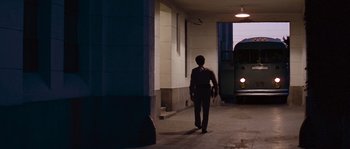 Movie still from “Assault on Precinct 13” (1976), directed by John Carpenter – A man walking down a street with a bus in front of him; Wide shot, Low angle