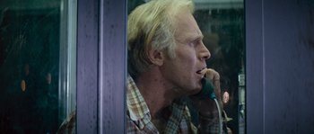 Movie still from “Assault on Precinct 13” (1976), directed by John Carpenter – An older man talking on a phone while sitting in a booth; Close Up shot, Over the shoulder angle