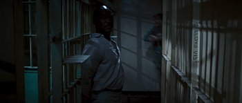 Movie still from “Assault on Precinct 13” (1976), directed by John Carpenter – A man standing next to a door in a room; Medium shot, Over the shoulder angle