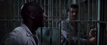 Movie still from “Assault on Precinct 13” (1976), directed by John Carpenter – Two men are in a jail cell with bars around them; Medium shot, Over the shoulder angle