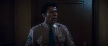 Movie still from “Assault on Precinct 13” (1976), directed by John Carpenter – A man in a police uniform is looking to his left; Close Up shot, Low angle