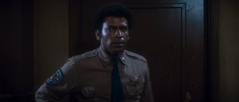 Movie still from “Assault on Precinct 13” (1976), directed by John Carpenter – A man in a police uniform is looking at the camera; Close Up shot, Low angle