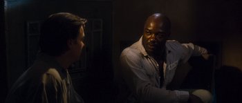 Movie still from “Assault on Precinct 13” (1976), directed by John Carpenter – Two men are talking in a dimly - lit room; Medium shot, Over the shoulder angle