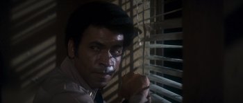 Movie still from “Assault on Precinct 13” (1976), directed by John Carpenter – A person wearing a suit and tie near a window; Close Up shot, Low angle