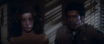 Movie still from “Assault on Precinct 13” (1976), directed by John Carpenter – A man and a woman are standing in a dark room; Close Up shot, Over the shoulder angle