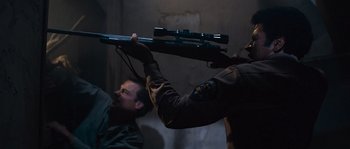 Movie still from “Assault on Precinct 13” (1976), directed by John Carpenter – A man holding a rifle over another man's head; Medium shot, High angle