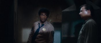 Movie still from “Assault on Precinct 13” (1976), directed by John Carpenter – A man in a uniform standing next to a wall; Medium shot, Over the shoulder angle