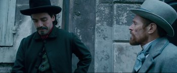 Movie still from “At Eternity's Gate” (2018), directed by Julian Schnabel – A man wearing a green coat and a black hat; Medium shot, Low angle