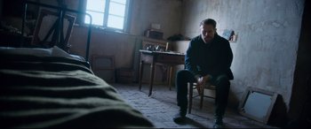 Movie still from “At Eternity's Gate” (2018), directed by Julian Schnabel – A man sitting on a chair in a room; Wide shot, High angle