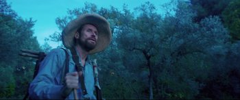 Movie still from “At Eternity's Gate” (2018), directed by Julian Schnabel – A man with a straw hat and a backpack; Medium shot, Low angle