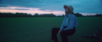 Movie still from “At Eternity's Gate” (2018), directed by Julian Schnabel – A man sitting on a chair in a field; Wide shot, Low angle