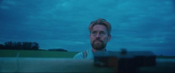 Movie still from “At Eternity's Gate” (2018), directed by Julian Schnabel – A man with a beard is looking into the distance; Medium shot, Low angle