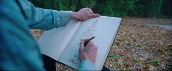 Movie still from “At Eternity's Gate” (2018), directed by Julian Schnabel – A person is writing in a book with a pen; Close Up shot, High angle