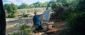 Movie still from “At Eternity's Gate” (2018), directed by Julian Schnabel – A man sitting in a chair and painting a picture; Wide shot, High angle