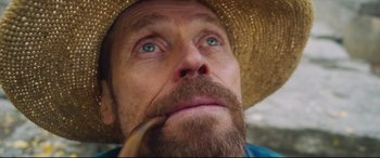 Movie still from “At Eternity's Gate” (2018), directed by Julian Schnabel – A person wearing a straw hat and holding a pipe; Extreme Close Up shot, Low angle