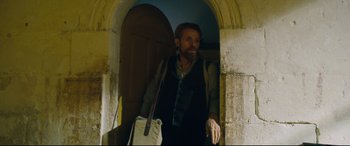 Movie still from “At Eternity's Gate” (2018), directed by Julian Schnabel – A man with a beard is standing in an archway; Medium shot, Low angle